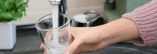 Glass of drinking water beside a simplified diagram showing common methods to filter fluoride from tap water.