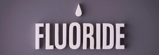 Glass of filtered drinking water beside a home fluoride removal filter in a bright New Zealand kitchen